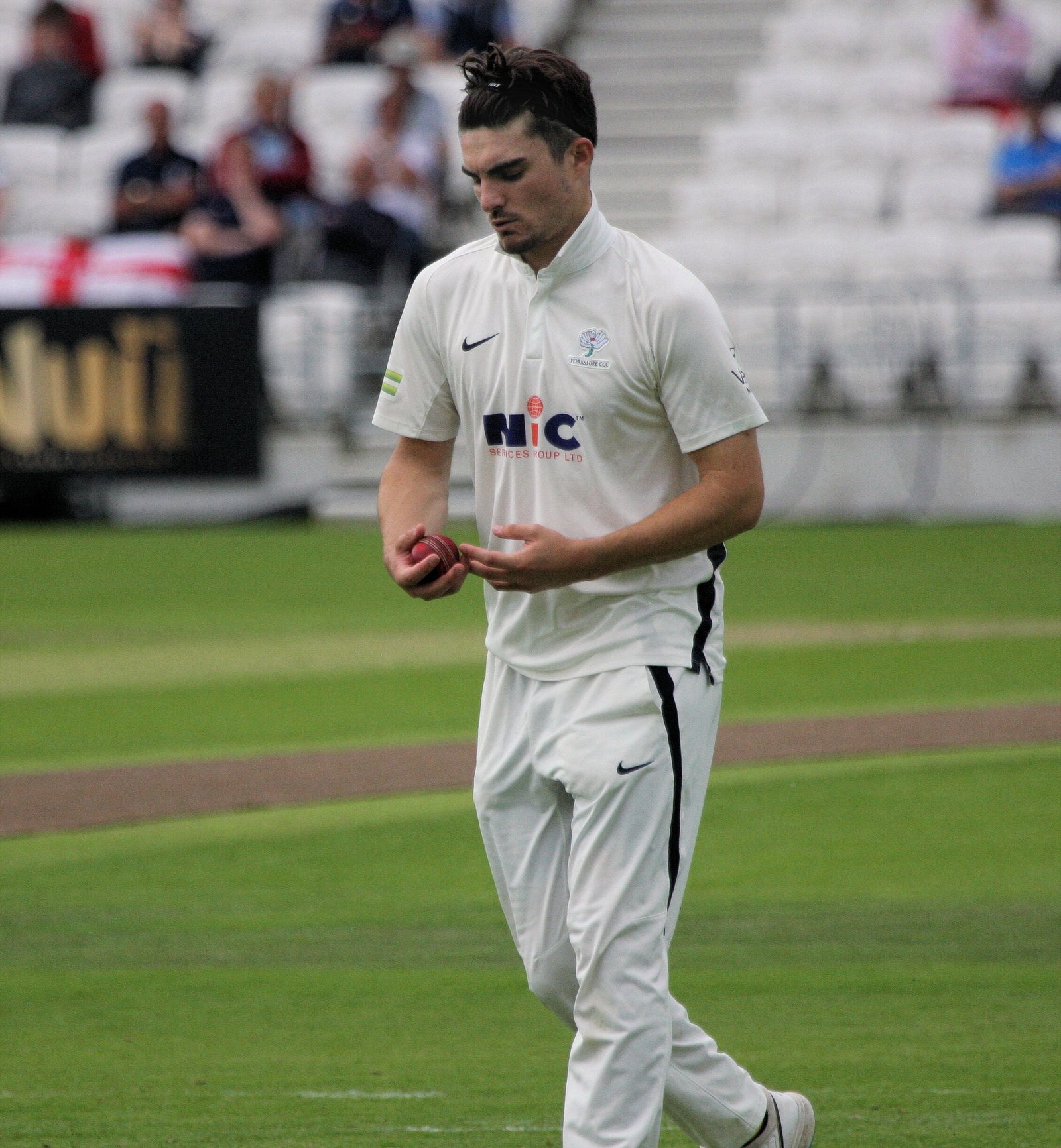 Jordan Thompson holding a red cricket ball while playing for Yorkshire in 2021